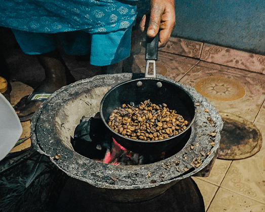 man roasting beans over fire